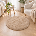 Khaki round plush area rug styled beside a bed and reading chair.