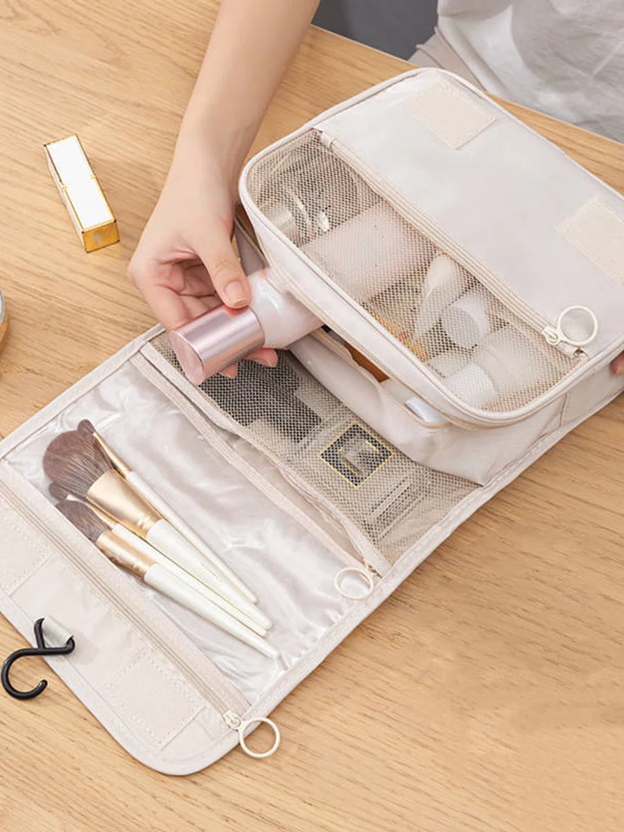 Open beige toiletry bag showing mesh and clear storage compartments