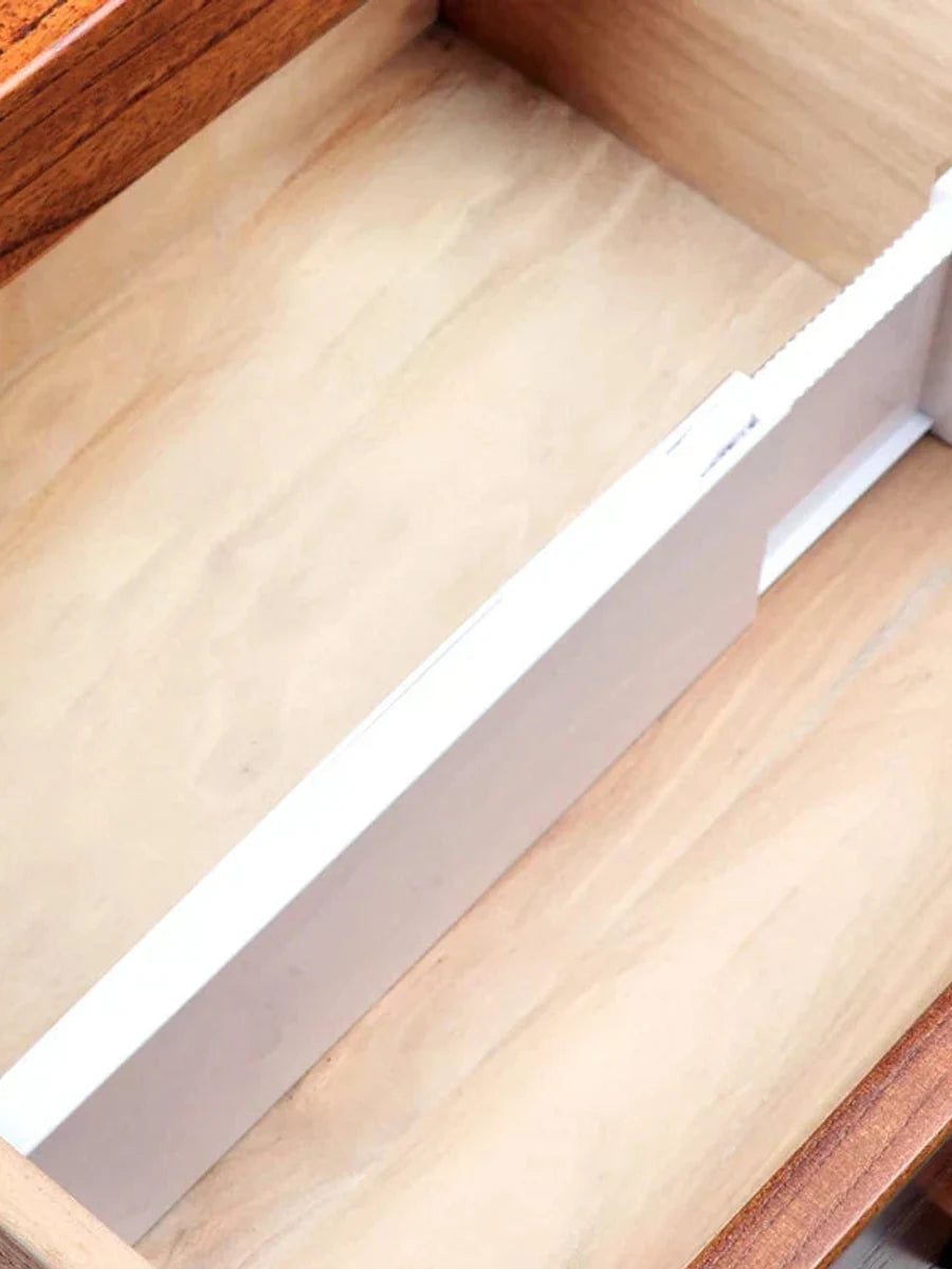 Close view of a white adjustable divider installed in a wood drawer