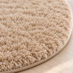 Close-up of the finished edge and plush surface of a khaki round area rug.