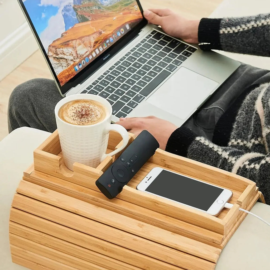 Bamboo couch cup holder tray holding a mug, phone and remote