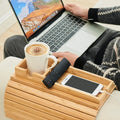 Bamboo couch cup holder tray holding a mug, phone and remote