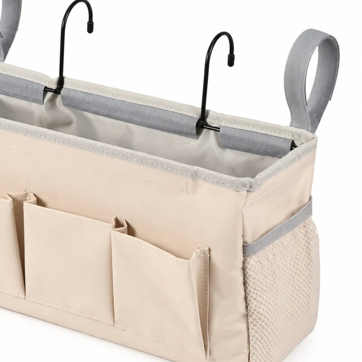Close view of the beige bedside caddy side mesh pocket, front pockets and reinforced hanging hardware