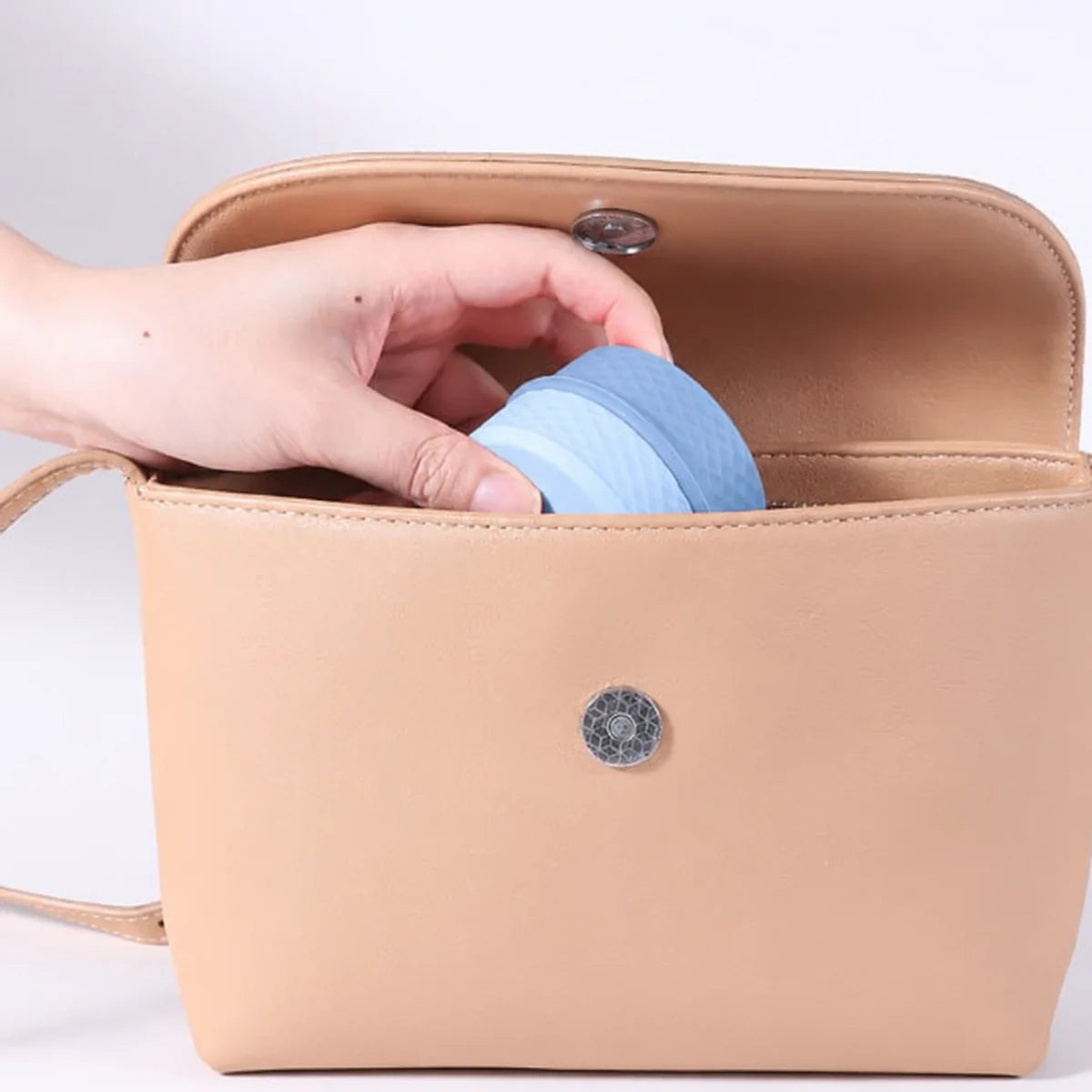 Blue cosmetic storage organizer being placed inside a travel bag