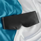 Black soft sleep mask displayed on satin fabric