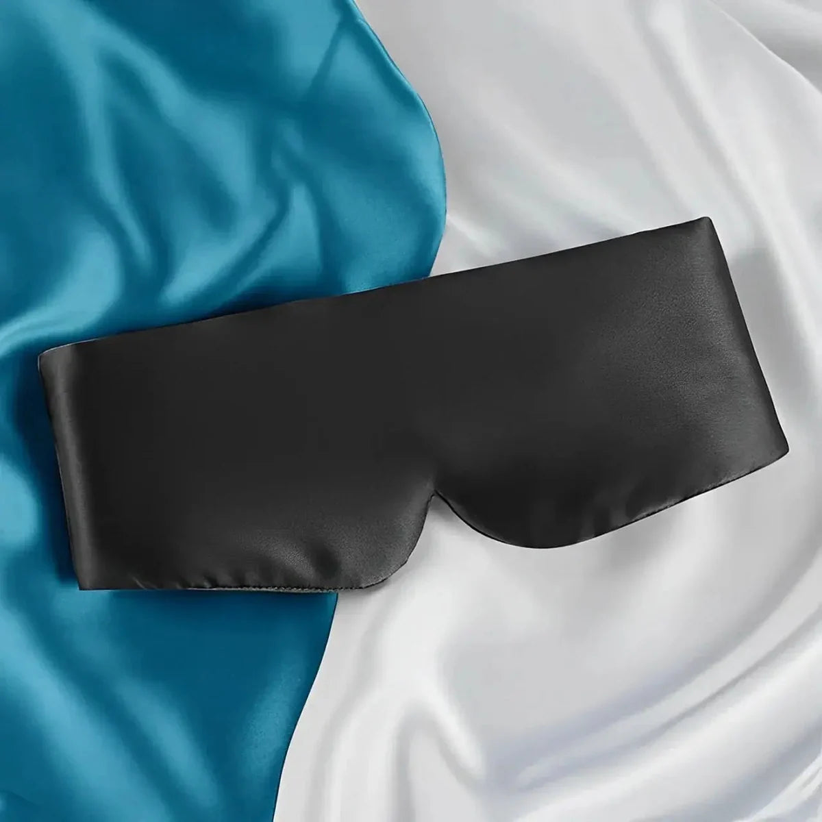 Black soft sleep mask displayed on satin fabric