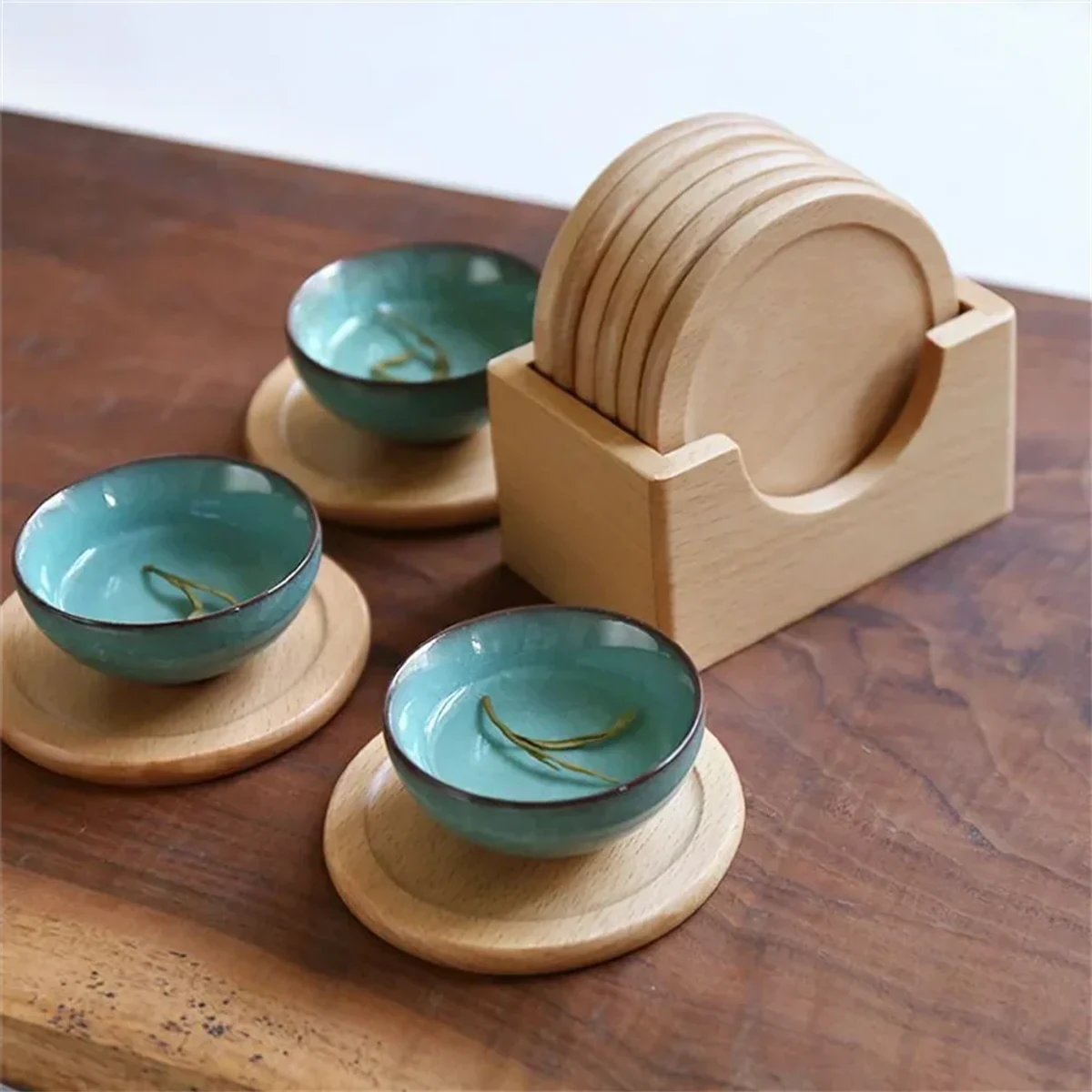 Six light beech wood round coasters with raised rims and matching wooden holder